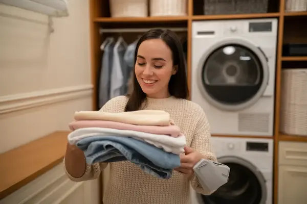 happy homeowner folding freshly dried clothes in a laundry room