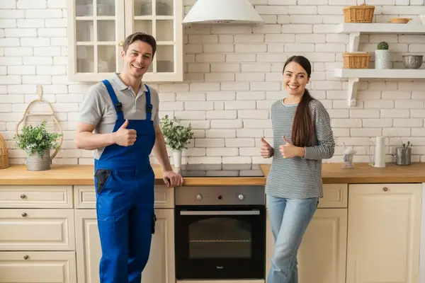 oven repair specialist standing next to a repaired oven