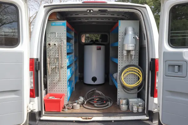 service van interior stocked with plumbing tools, pipes, and spare parts for hot water tank repair